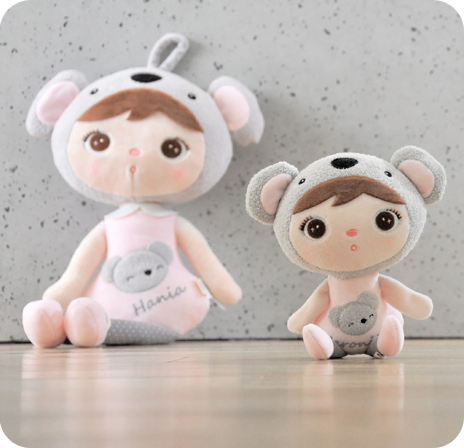 Dwie lalki Metoo siedzą na podłodze. Przebrane są za koale w różowych ubrankach. Jednak jest dużą lalą, a druga małą lalą.