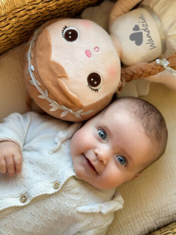 Dziewczynka w łóżeczku z laleczką Metoo personalizowanym Aniołkiem