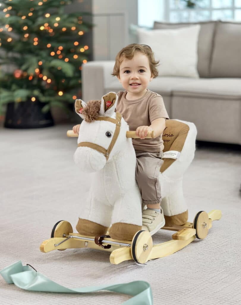 Roczny chłopiec siedzi na koniku na biegunach. Prezent na boże narodzenie.